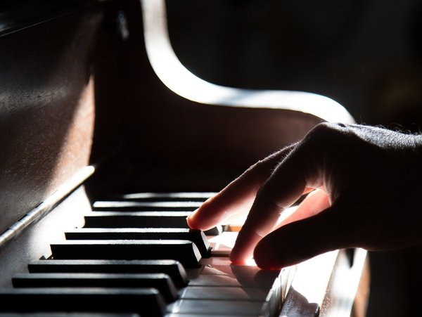 Eine Nahaufnahme von Klaviertasten, die mit einer Hand bespielt werden wird gezeigt.
