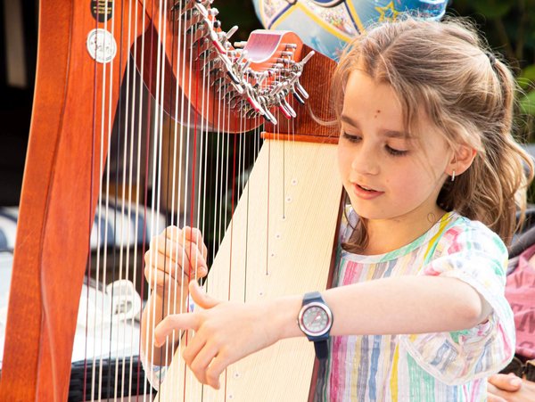 Ein junges Mädchen bespielt eine Harfe.